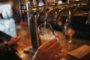 Bartender pouring beer in glass pint