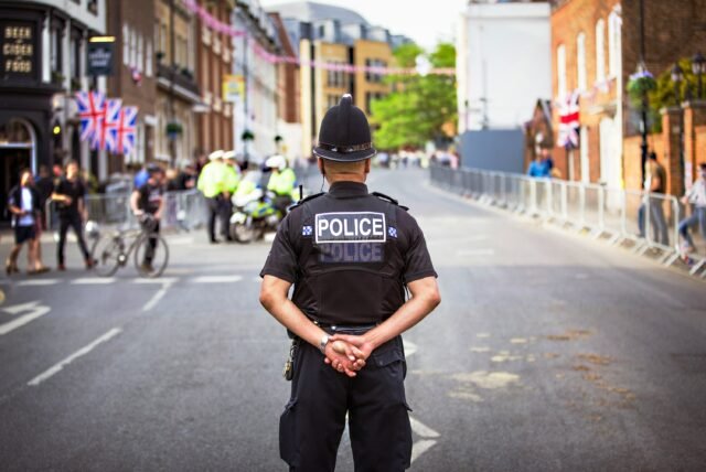 Police standing in the middle of the road surrounded by pubs, people crossing the road and police officers in the back blurred