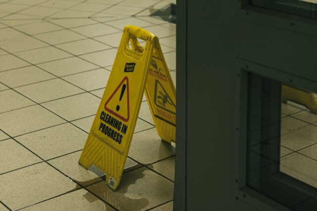 A yellow caution sign placed on a white tiled floor